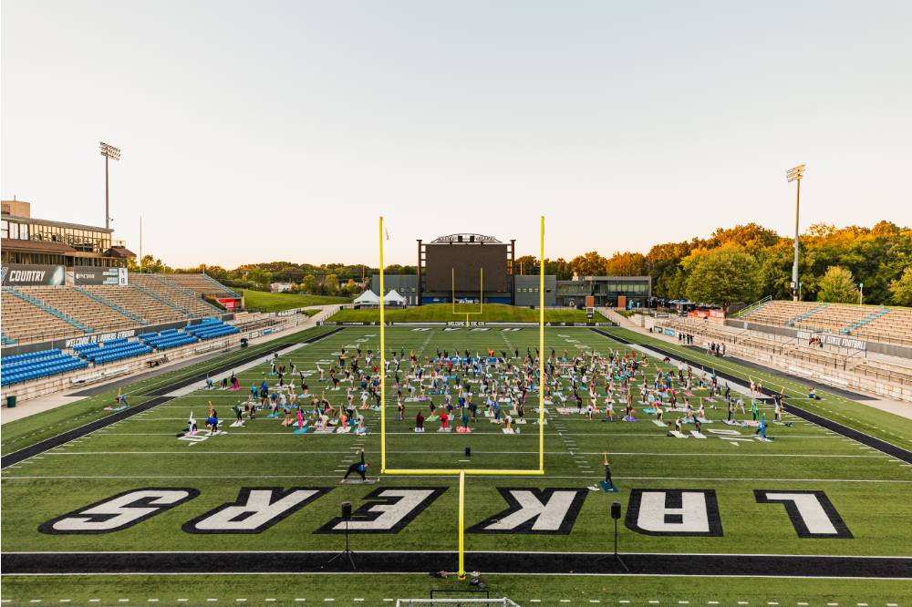 aerial view of students doing yoga at the football field